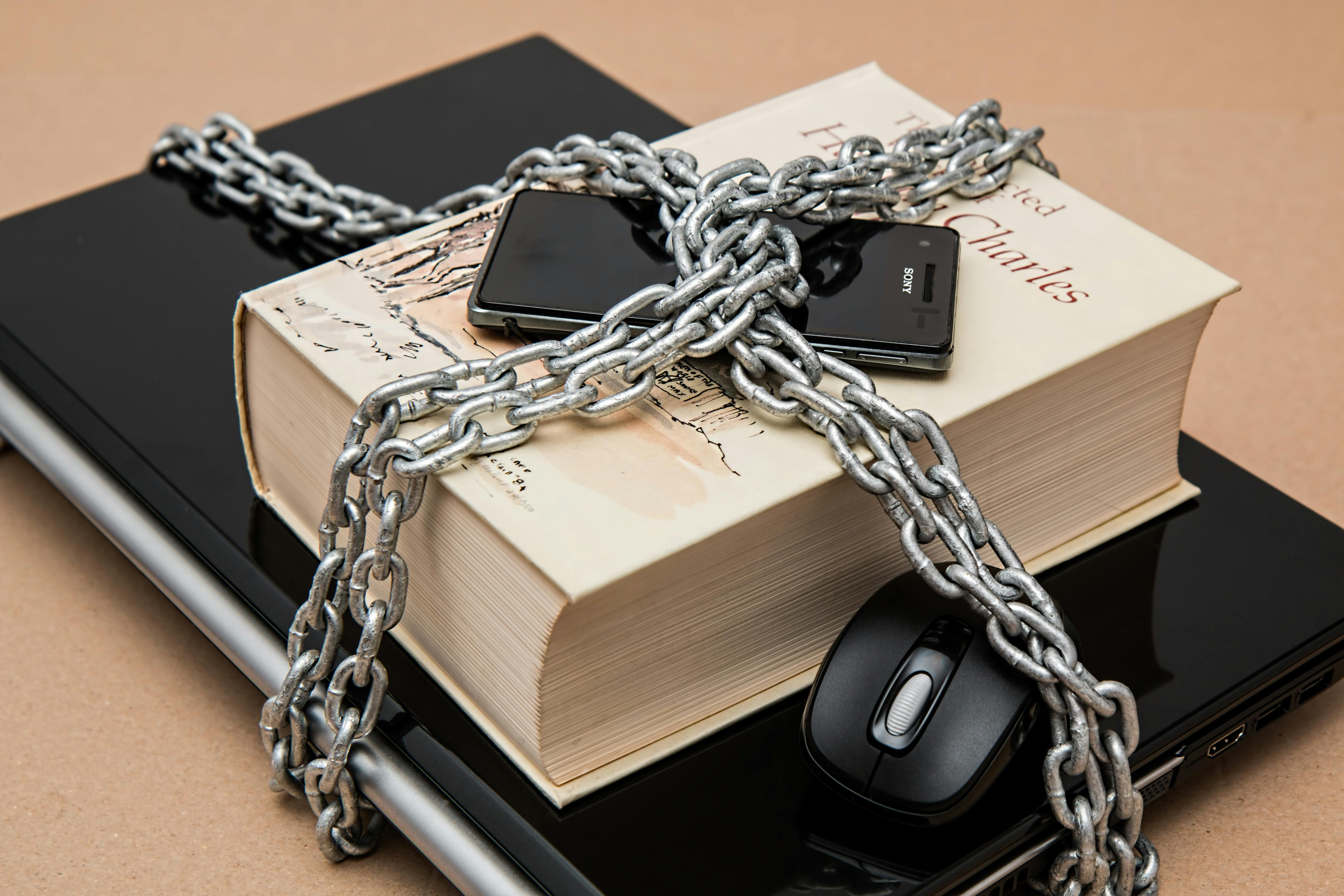 A laptop, mouse and book locked up with chains